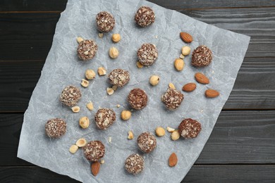 Photo of Delicious sweet chocolate candies and nuts on dark wooden table, top view