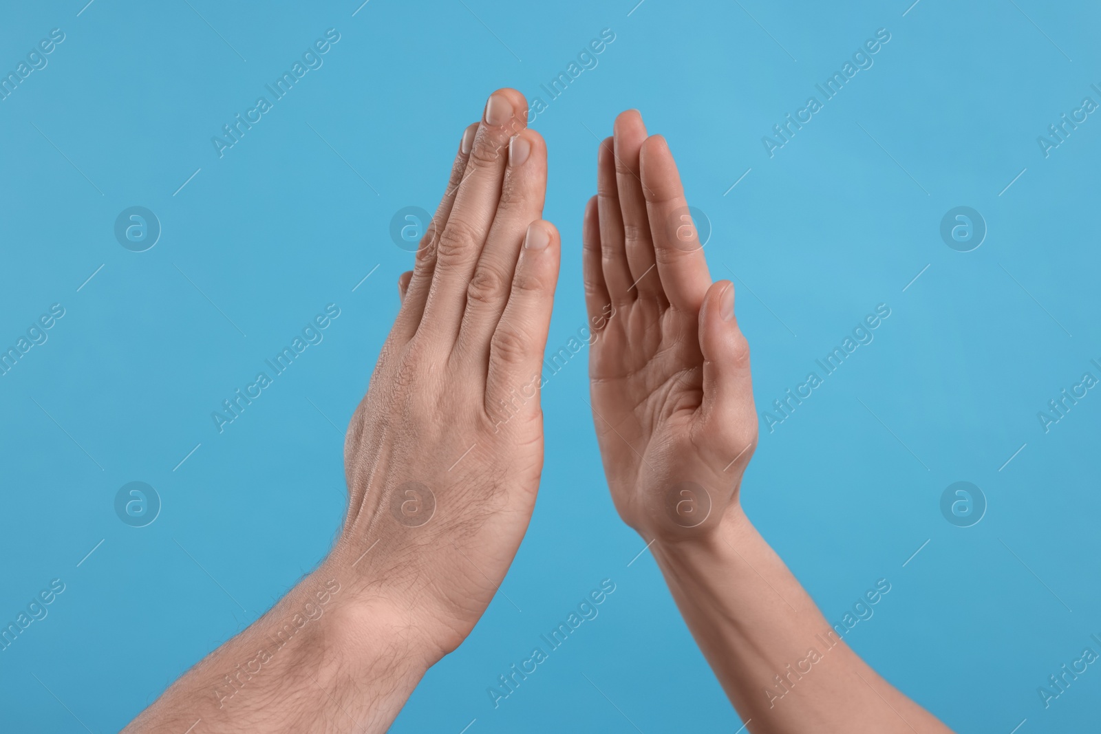 Photo of People giving high five on light blue background, closeup