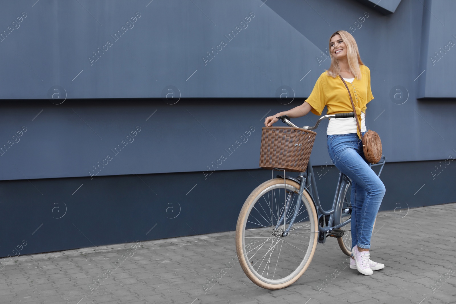 Photo of Woman with bicycle on street near gray wall