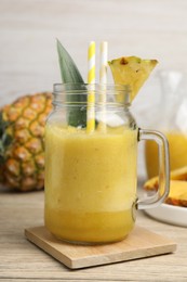 Photo of Tasty pineapple smoothie and fruit on wooden table, closeup