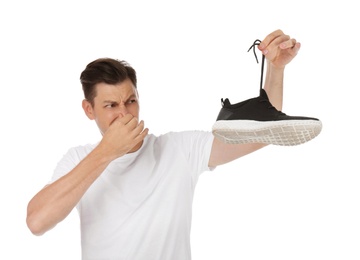 Photo of Man feeling bad smell from shoe on white background. Air freshener