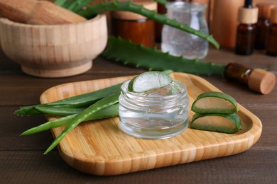 Photo of Jar with natural gel and aloe vera leaves on wooden table