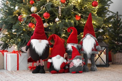 Photo of Funny decorative gnomes and gift boxes under Christmas tree indoors