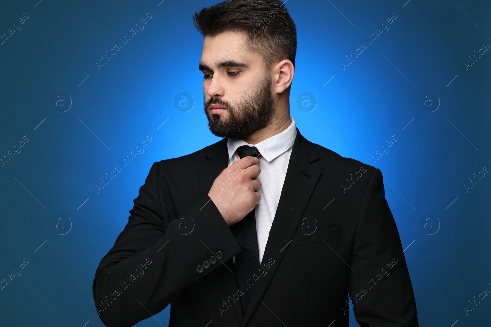 Photo of Handsome businessman in suit and necktie on blue background