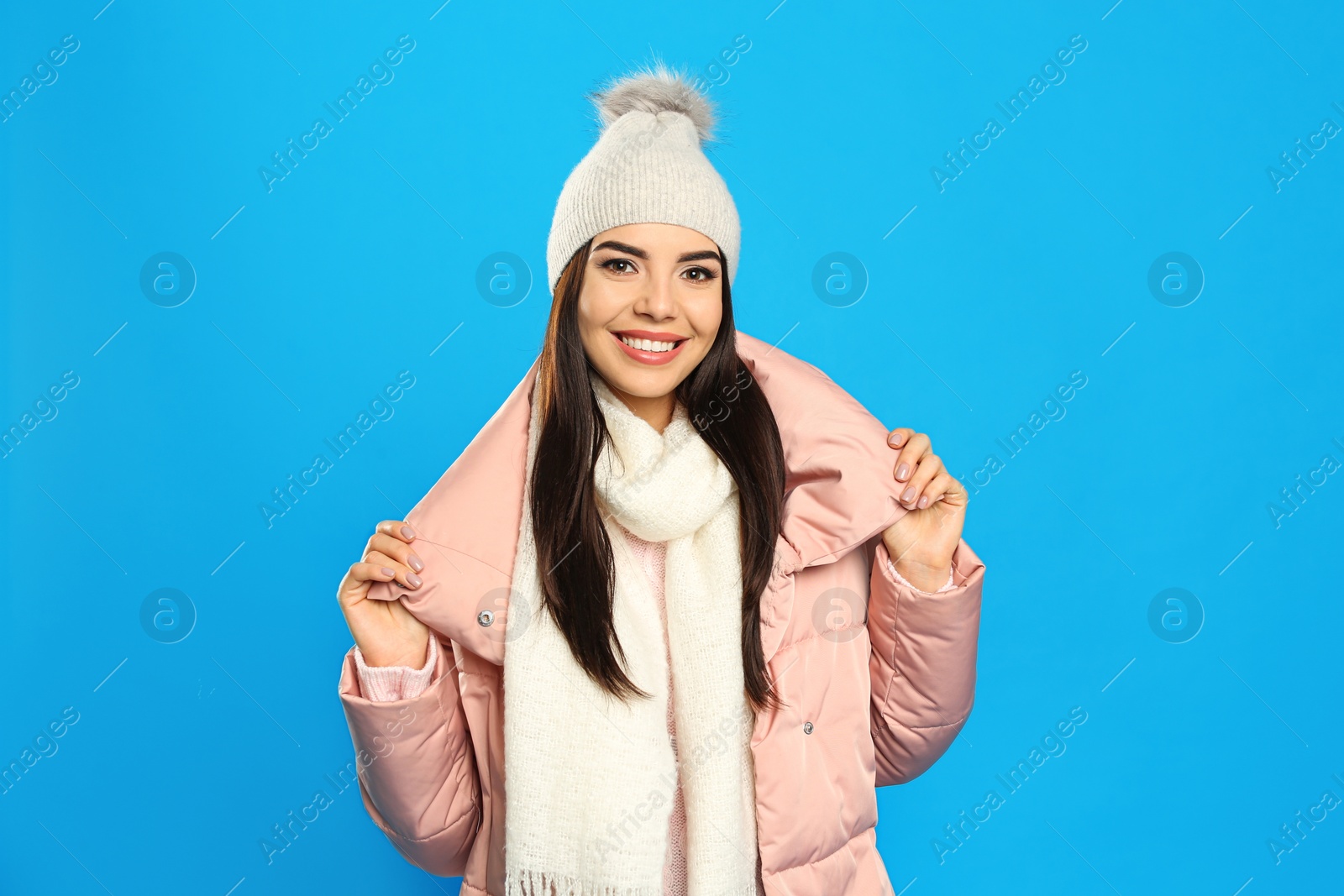 Photo of Happy young woman in warm clothes on blue background. Winter vacation