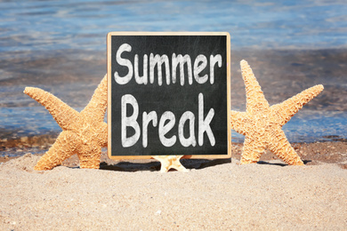 Image of Small chalkboard with inscription Summer Break on sand near sea. School Holidays 