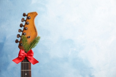 Photo of Guitar with bow and fir tree twig on color background. Christmas music concept