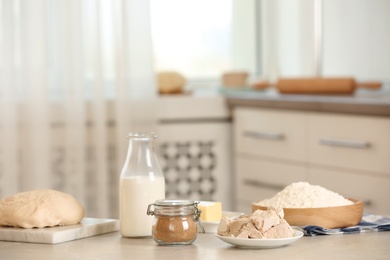 Photo of Yeast and dough ingredients on white table indoors, space for text