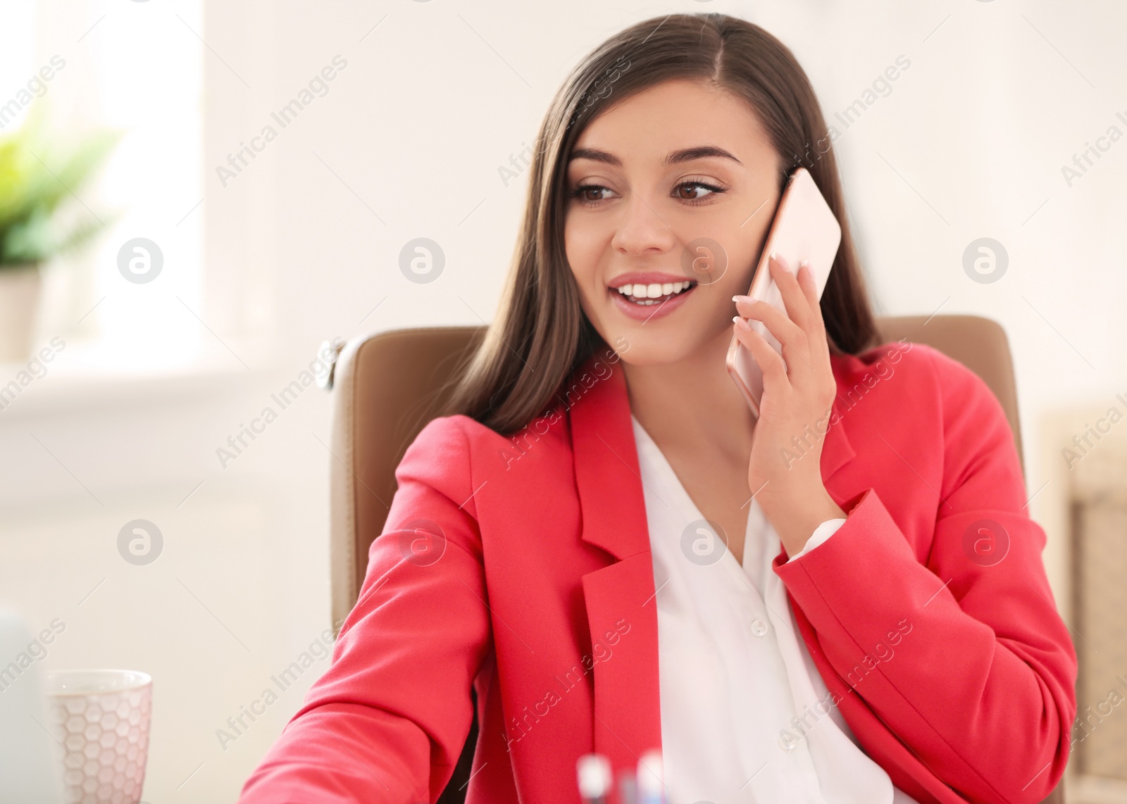 Photo of Young woman talking on phone at workplace