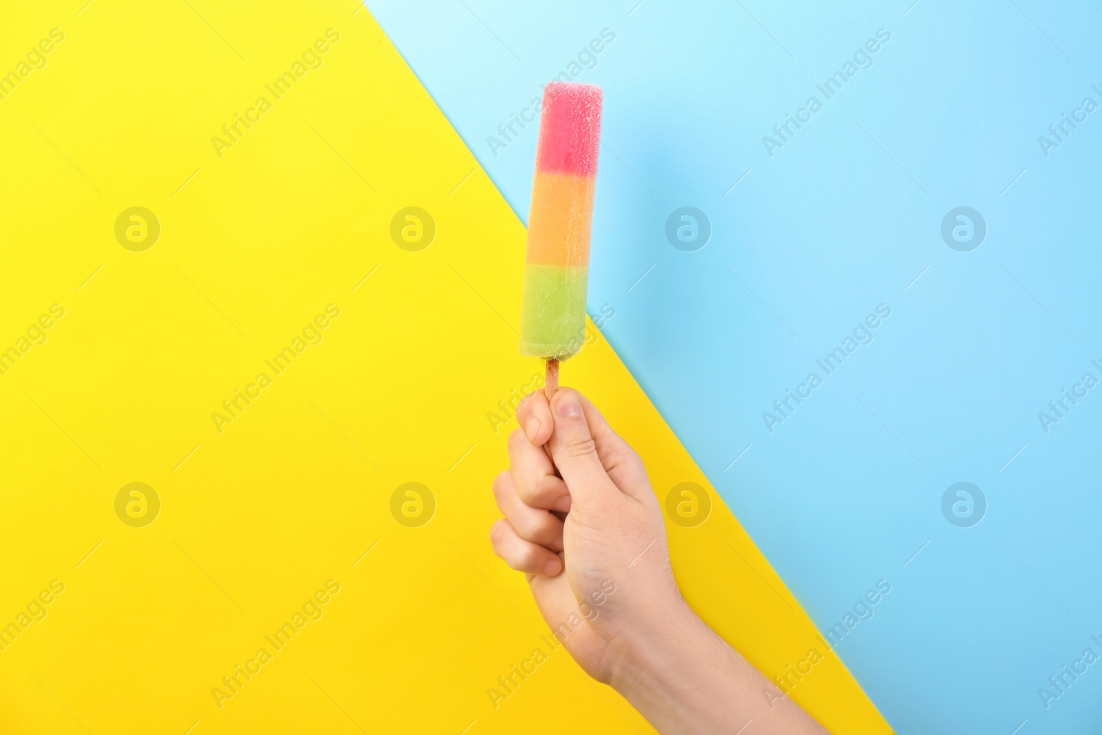 Photo of Man holding yummy ice cream on color background. Focus on hand