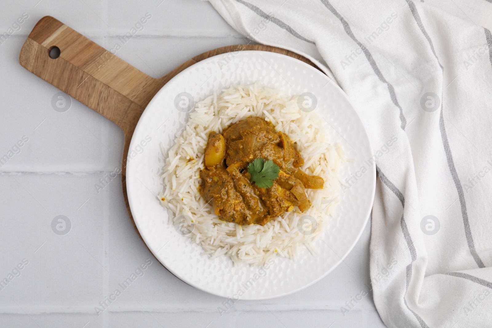 Photo of Delicious chicken curry with rice on white tiled table, top view