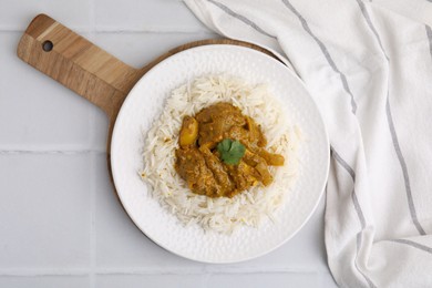 Photo of Delicious chicken curry with rice on white tiled table, top view