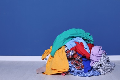 Pile of dirty clothes on floor near color wall