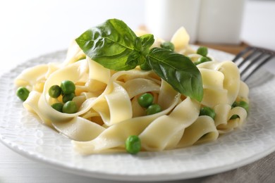 Photo of Delicious pasta with green peas served on white table, closeup