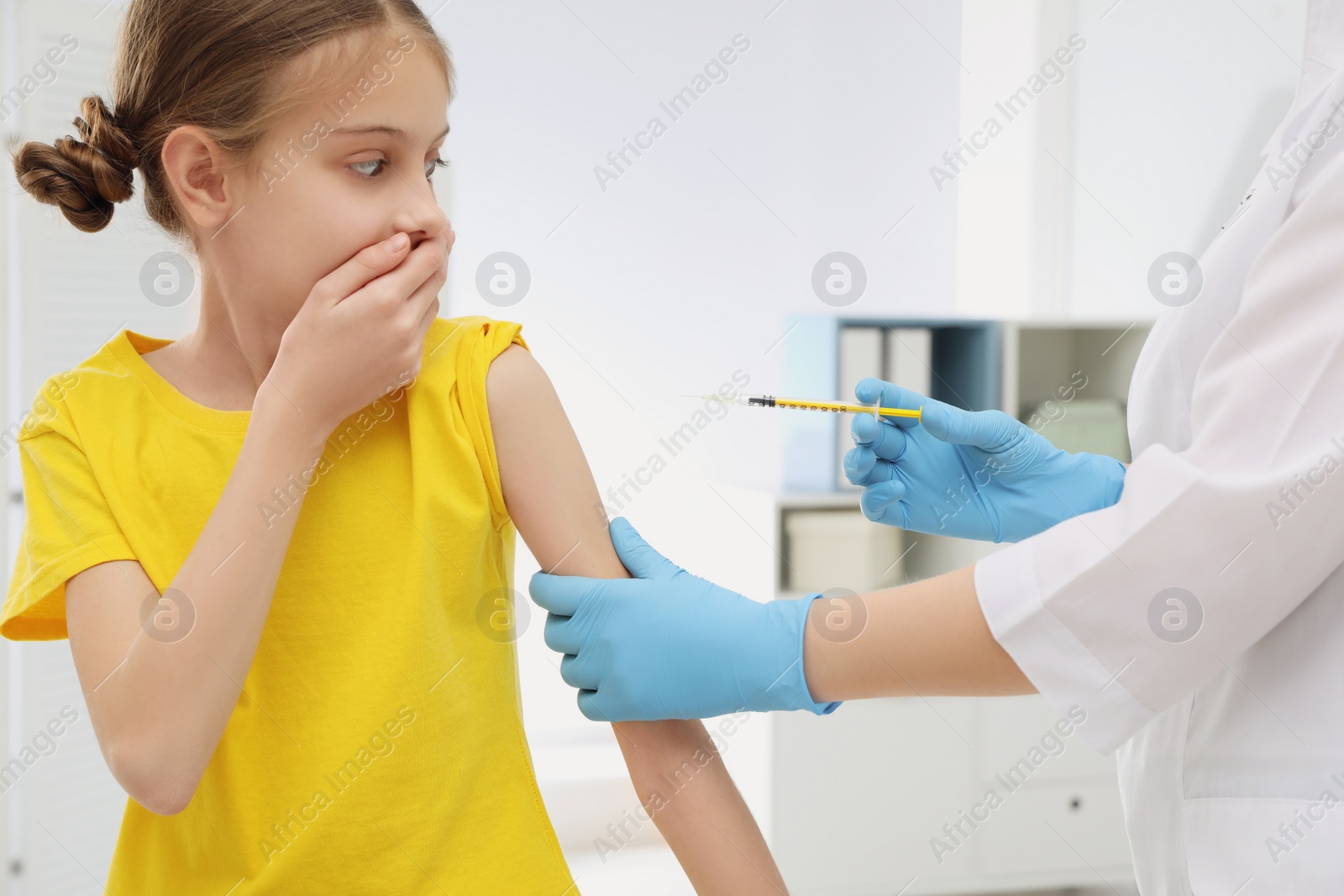 Photo of Doctor giving injection to little girl in hospital. Immunization concept