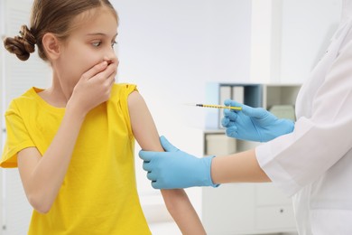 Doctor giving injection to little girl in hospital. Immunization concept