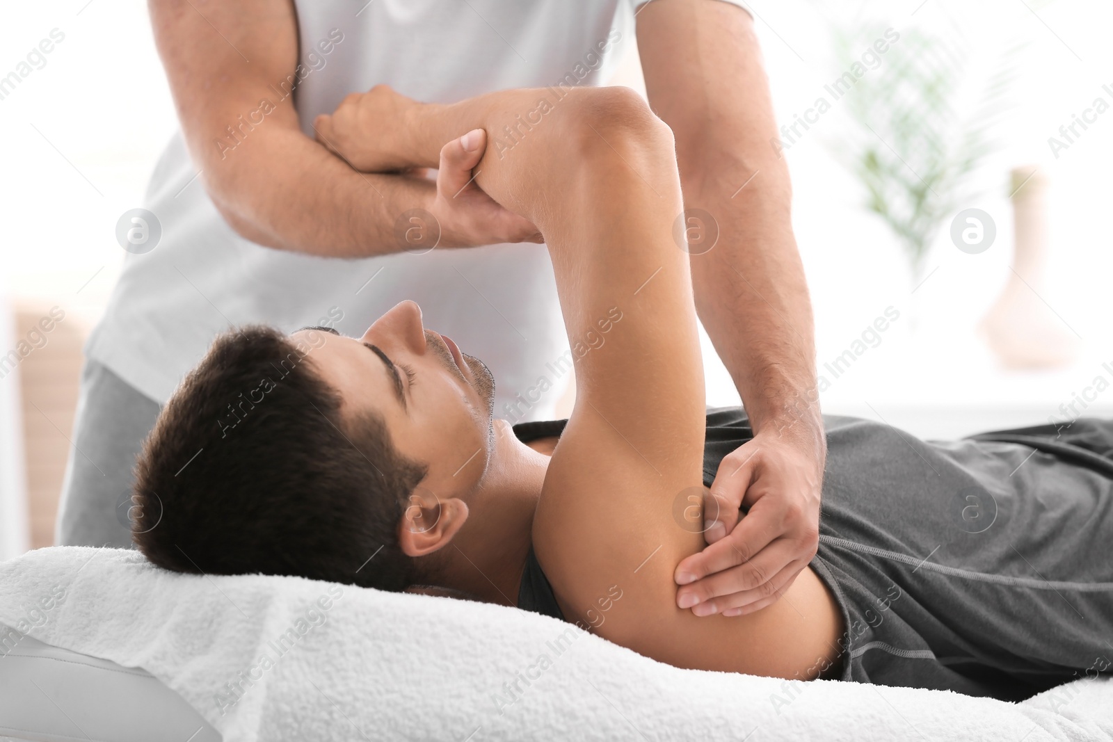 Photo of Young man receiving massage in salon, closeup