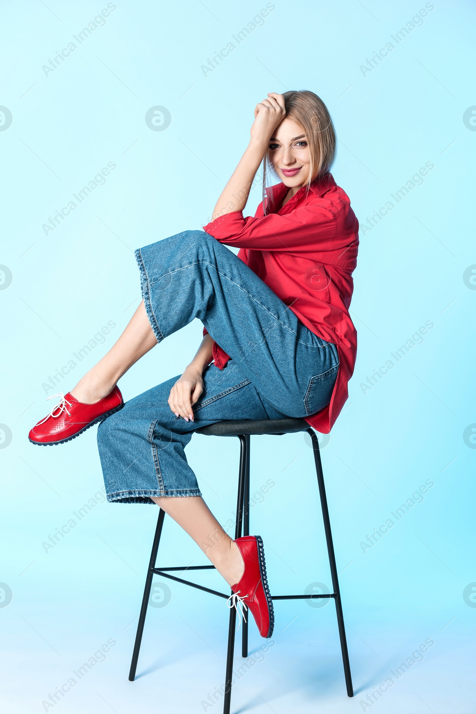 Photo of Fashionable woman in stylish shoes on stool against color background