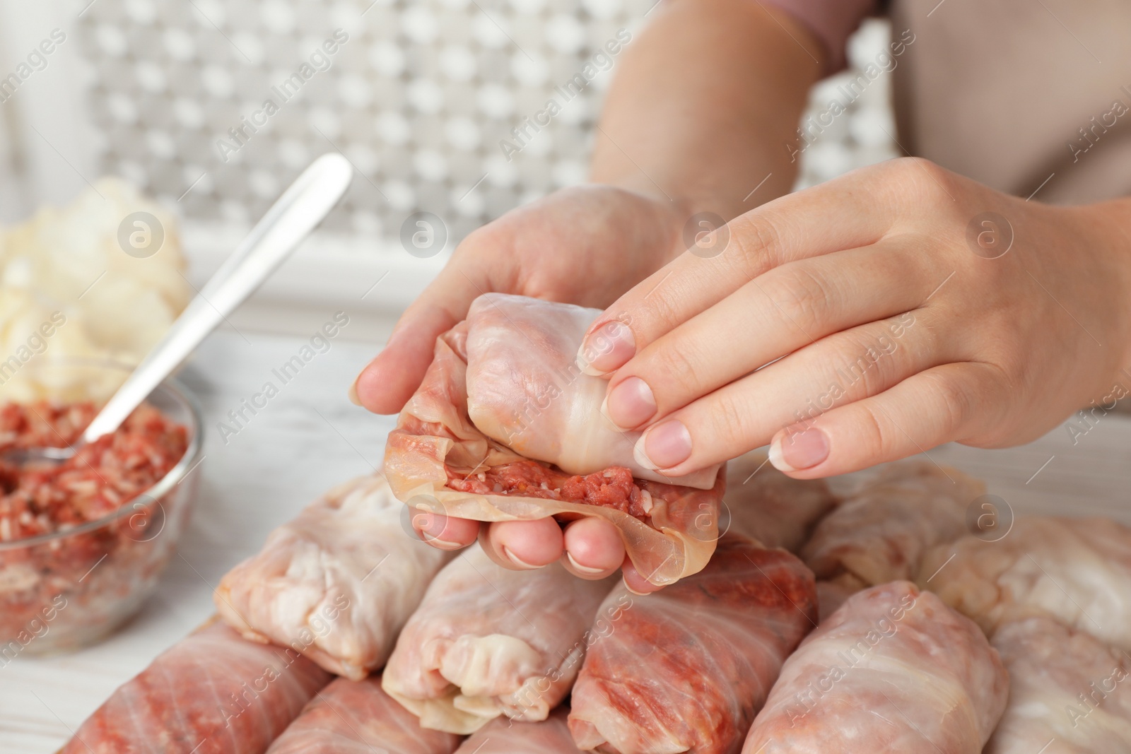 Photo of Woman making stuffed cabbage roll at table, closeup