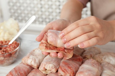 Woman making stuffed cabbage roll at table, closeup