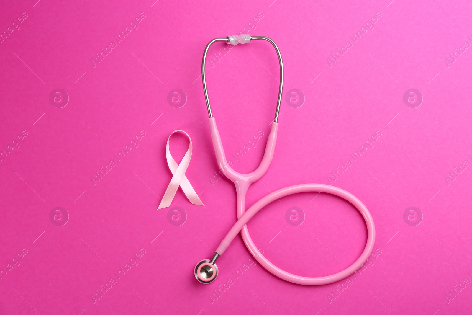 Photo of Pink ribbon as breast cancer awareness symbol and stethoscope on color background, flat lay