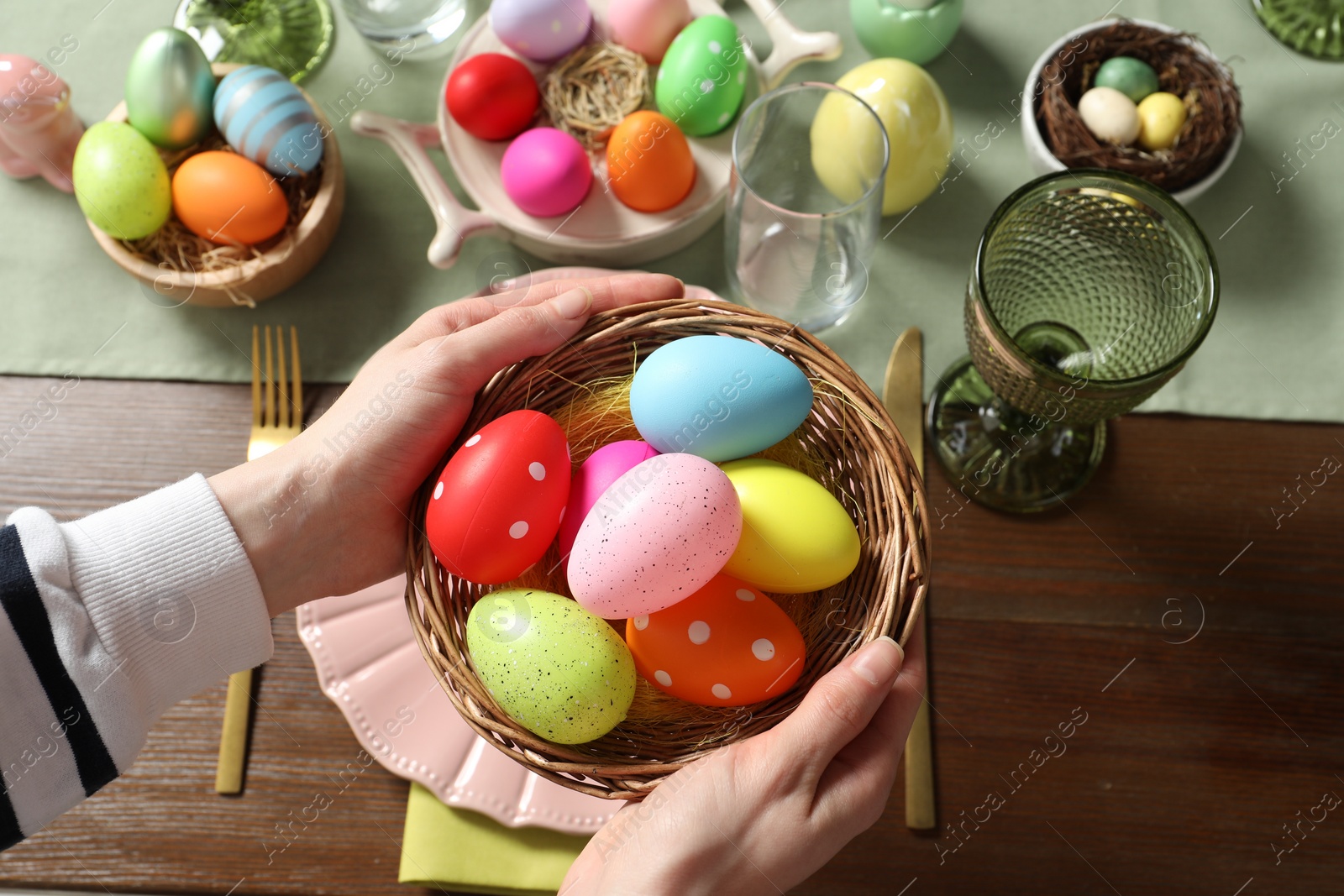 Photo of Woman setting table for festive Easter dinner at home, above view