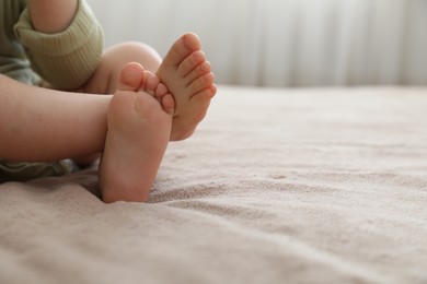 Photo of Baby sitting on bed at home, closeup. Space for text