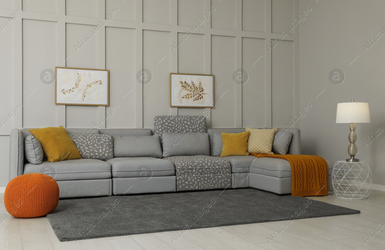 Photo of Comfortable large sofa with cushions and knitted blanket in living room