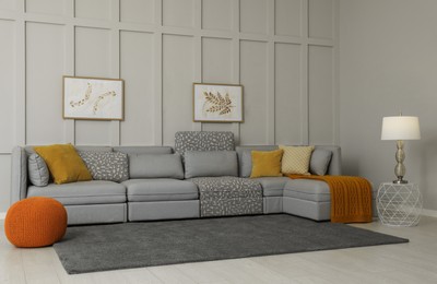 Photo of Comfortable large sofa with cushions and knitted blanket in living room