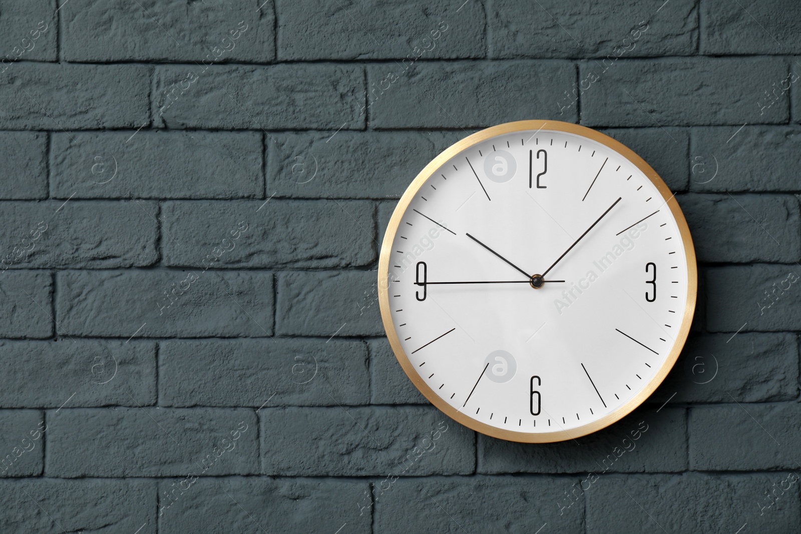 Photo of Modern clock on brick wall. Time concept