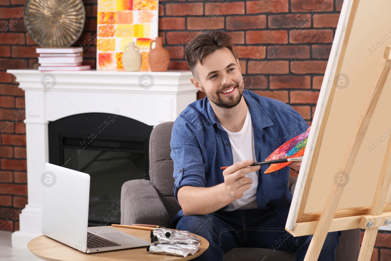 Photo of Happy man learning to draw with online course on laptop at home. Time for hobby