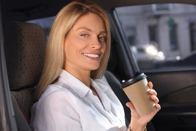 Coffee to go. Happy woman with paper cup of drink in car