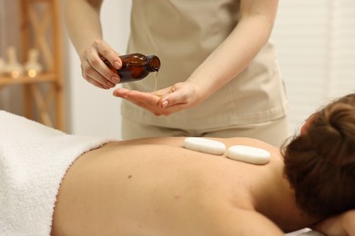 Photo of Aromatherapy. Woman receiving back massage with oil in spa salon, closeup