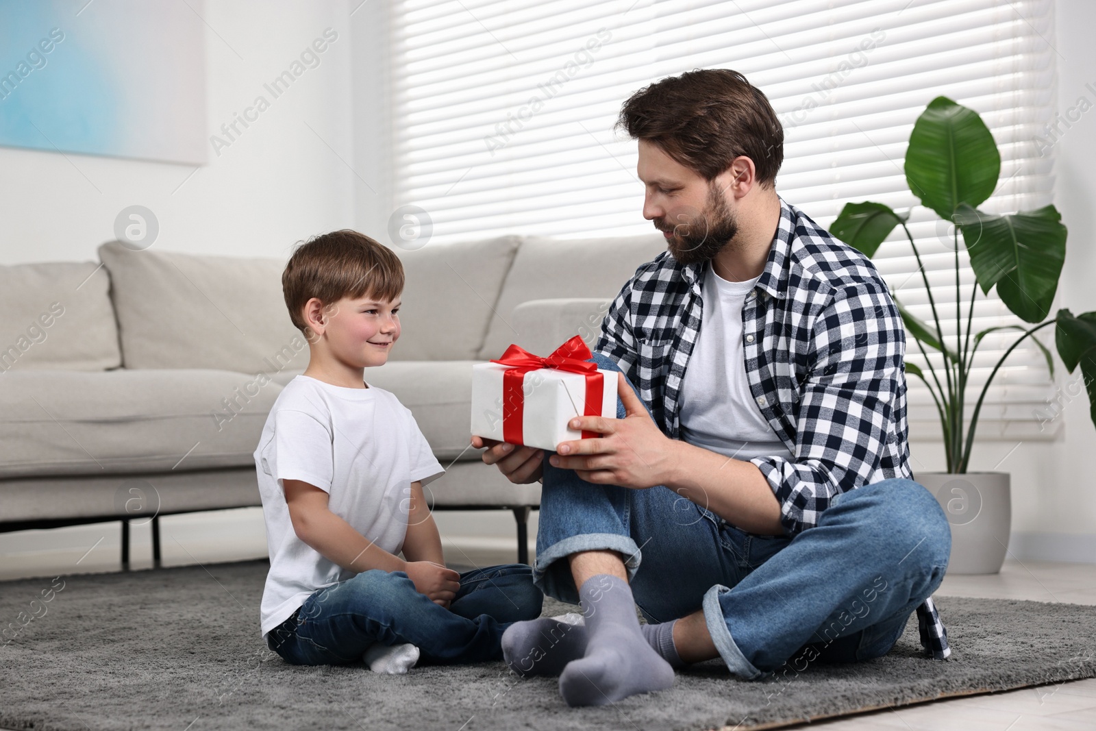 Photo of Dad with gift and greeting card for Father's Day from his son at home