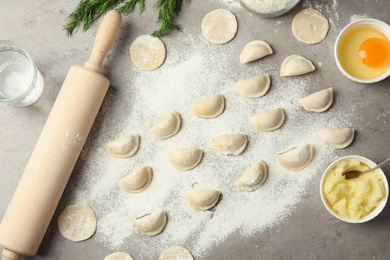 Photo of Flat lay composition with raw dumplings and ingredients on grey background. Process of cooking