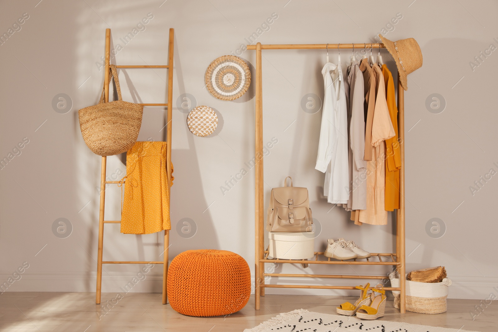 Photo of Modern dressing room interior with stylish clothes, shoes and orange pouf