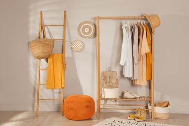 Modern dressing room interior with stylish clothes, shoes and orange pouf