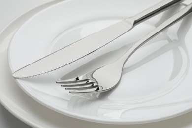 Clean plates, fork and knife, closeup view