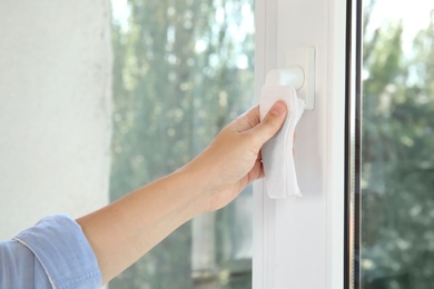 Photo of Woman using tissue paper to open window indoors, closeup