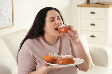 Photo of Lazy overweight woman eating buns at home