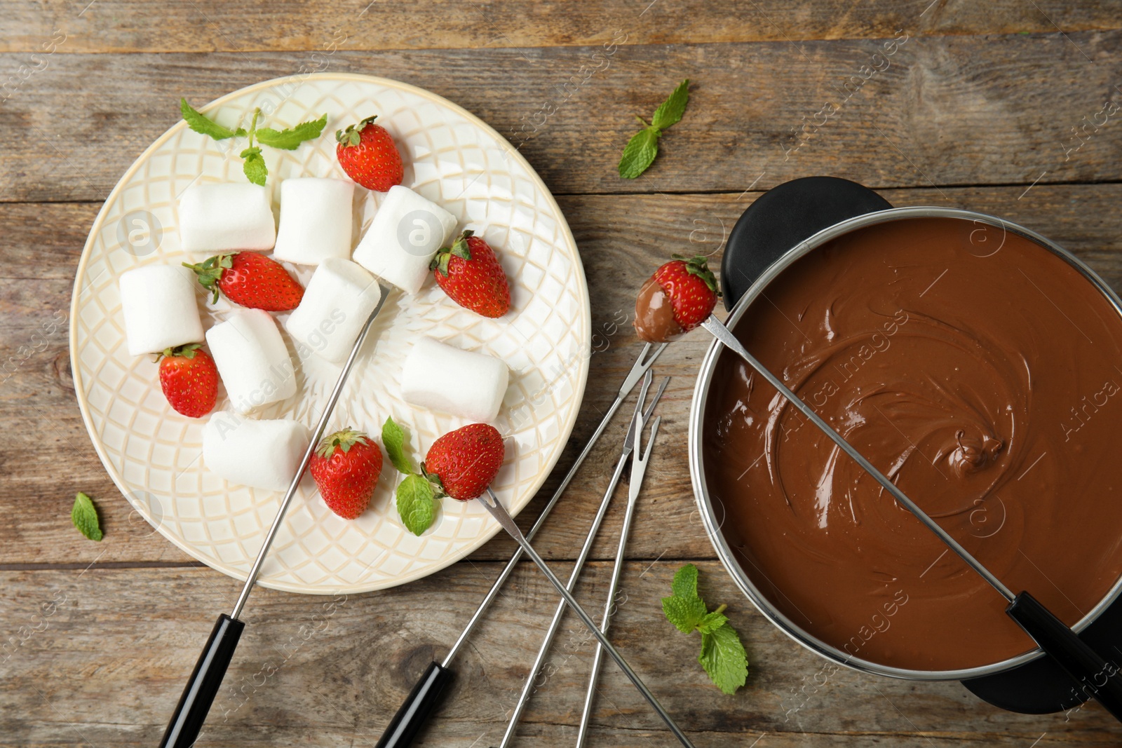 Photo of Flat lay composition with chocolate fondue in pot, strawberries and marshmallows on wooden background