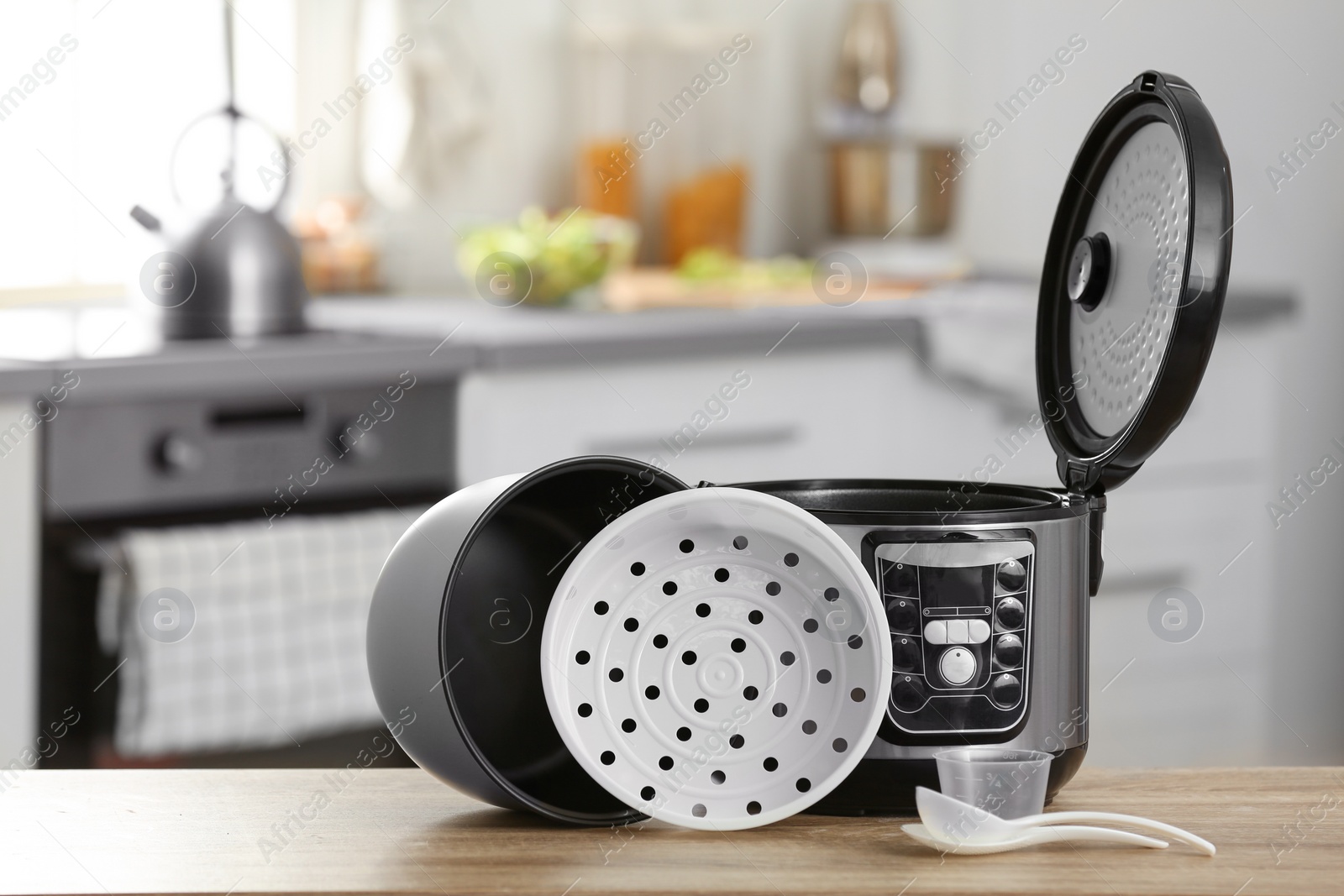 Photo of Modern electric multi cooker, parts and accessories on table in kitchen. Space for text