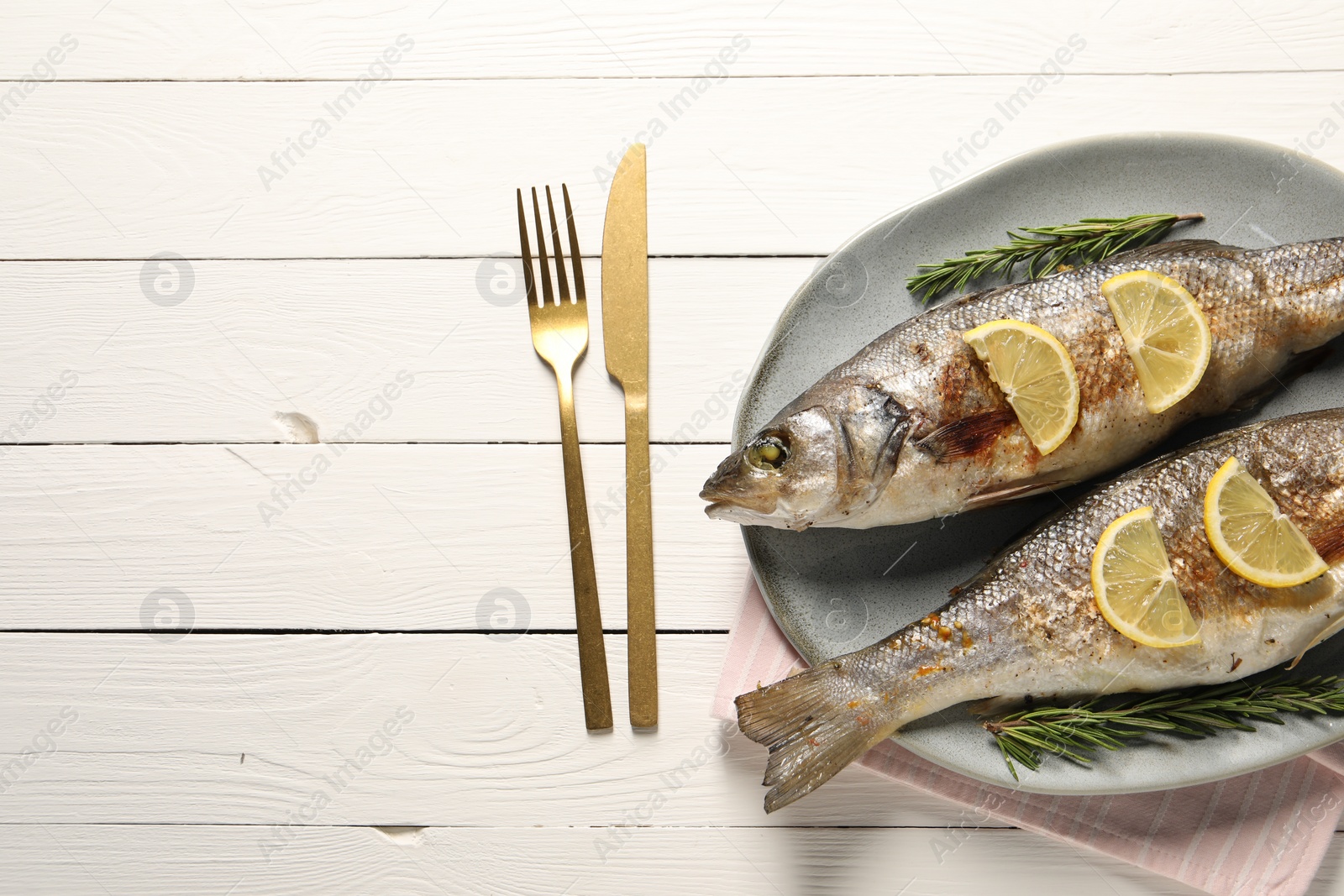 Photo of Delicious baked fish served on white wooden table, top view. Space for text