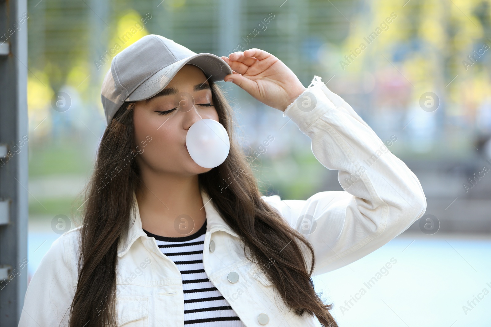 Photo of Beautiful young woman blowing bubble gum outdoors