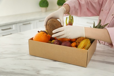 Photo of Woman with assortment of exotic fruits at table in kitchen, closeup