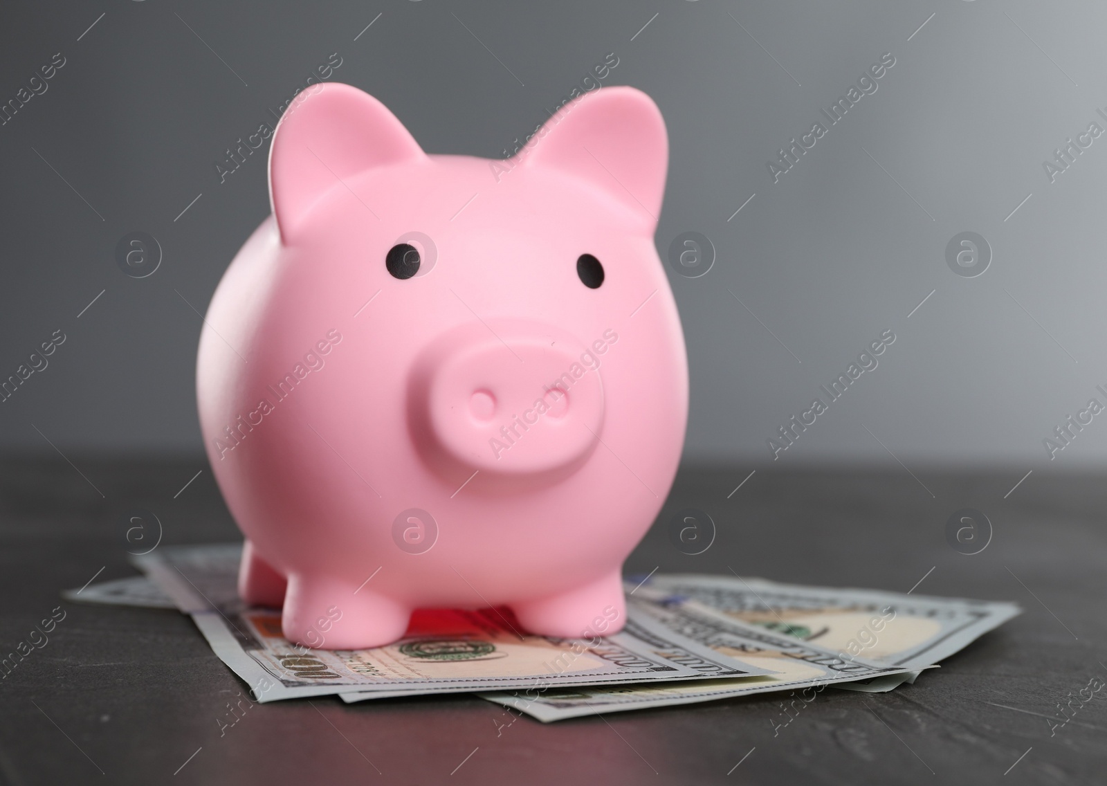 Photo of Pink piggy bank and banknotes on black table