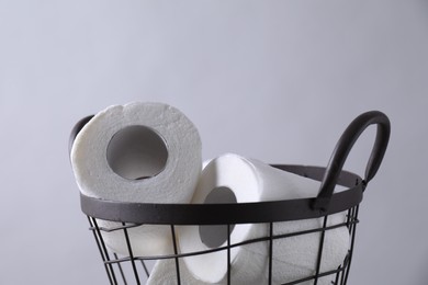 Photo of Toilet paper rolls in basket against light grey wall