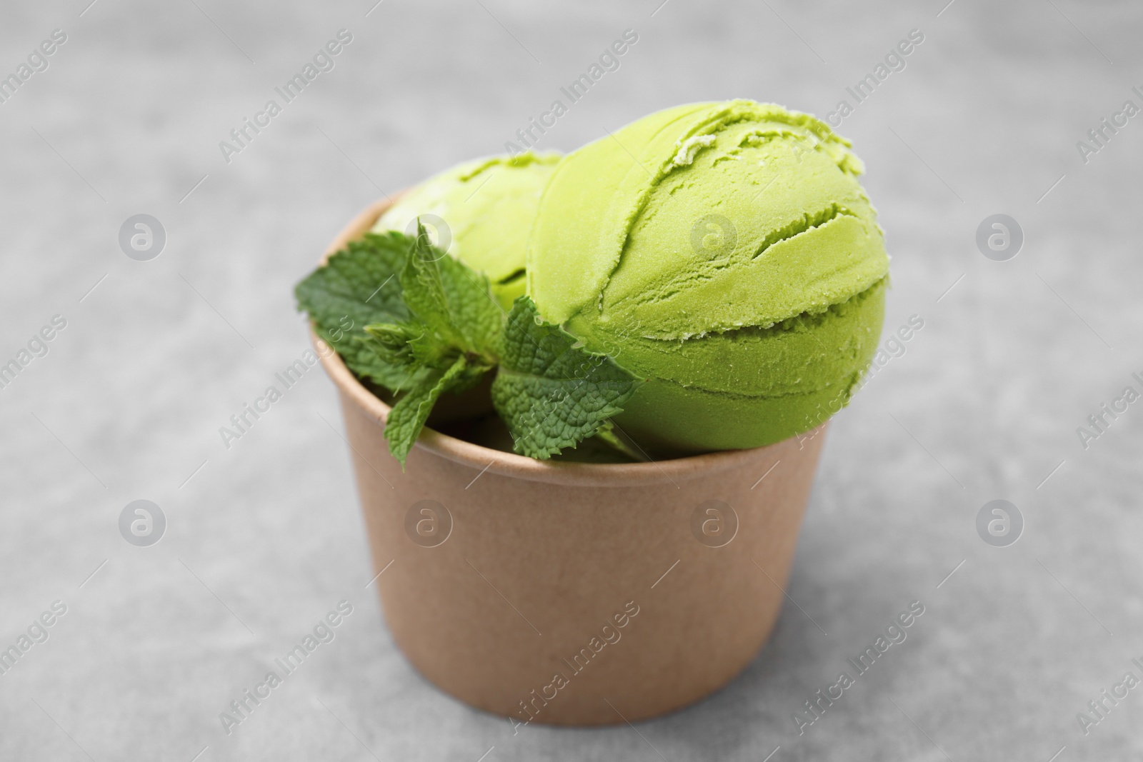 Photo of Paper cup with tasty matcha ice cream on grey table, closeup