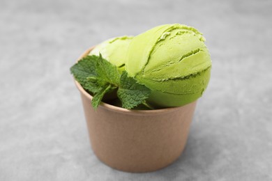 Paper cup with tasty matcha ice cream on grey table, closeup