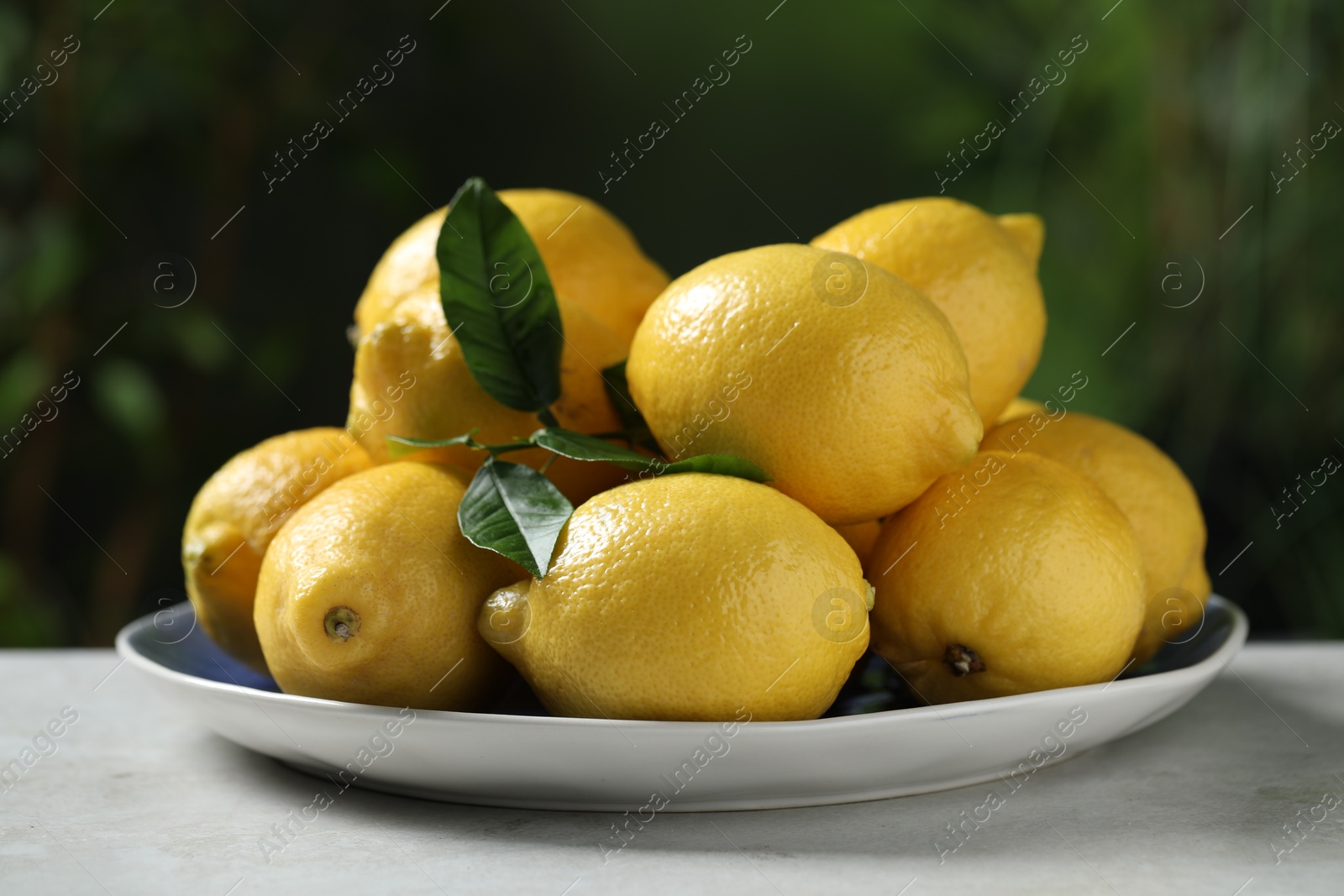 Photo of Fresh lemons and green leaves on table outdoors